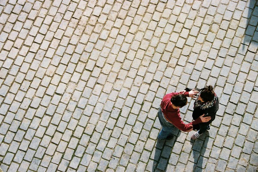 Two people standing on a cobblestone square